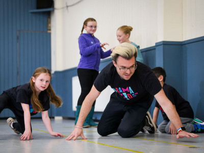 A Drama Kids teacher and children taking part in an imaginative movement exercise on the floor