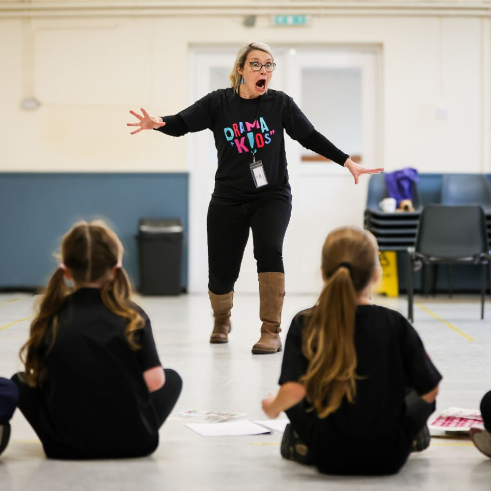 A Drama Kids teacher using an expressive pose while leading children through a drama activity