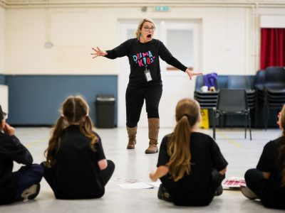 A Drama Kids teacher using an expressive pose while leading children through a drama activity